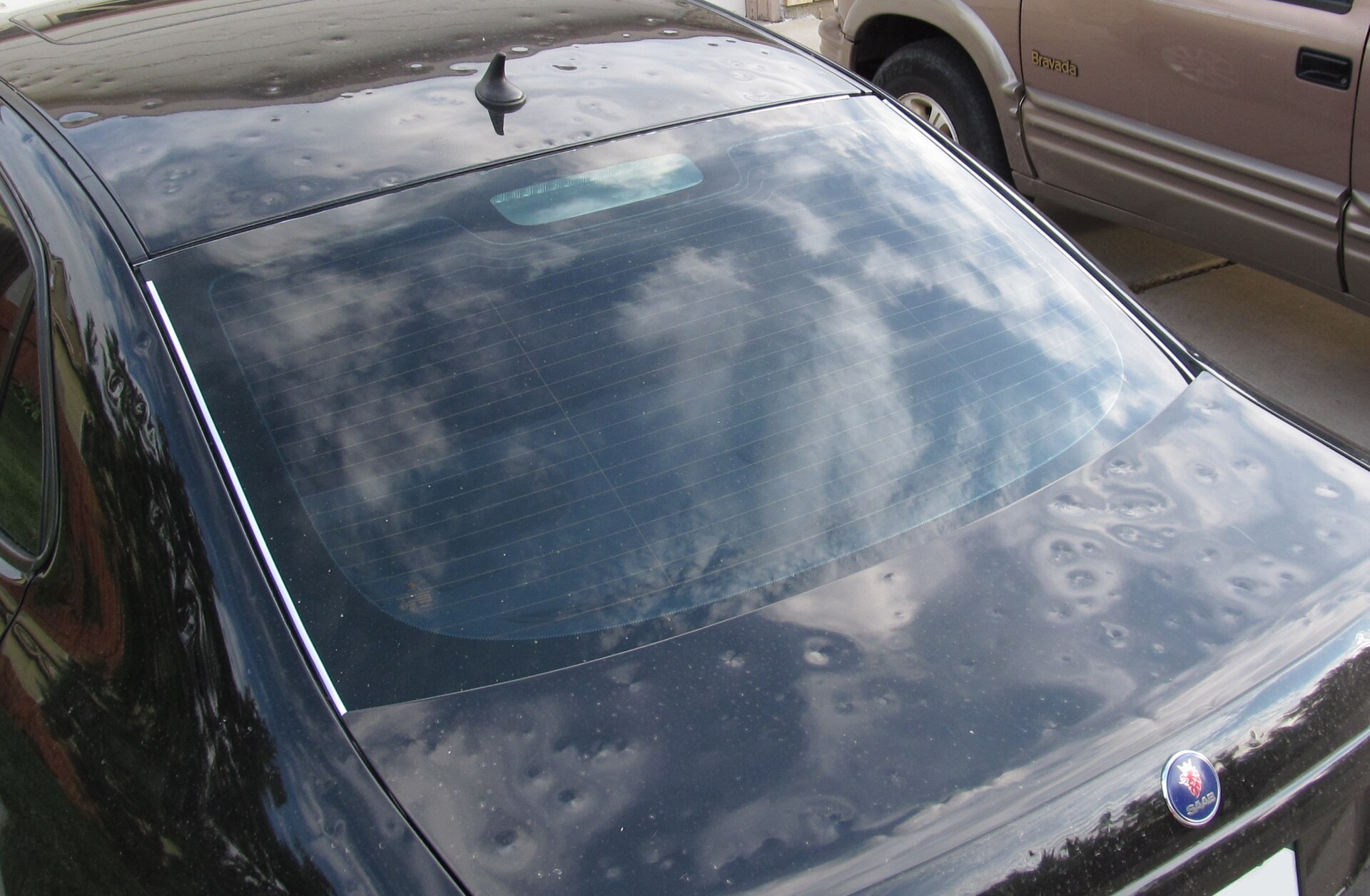 Black car panel covered in dozens of round hail dents