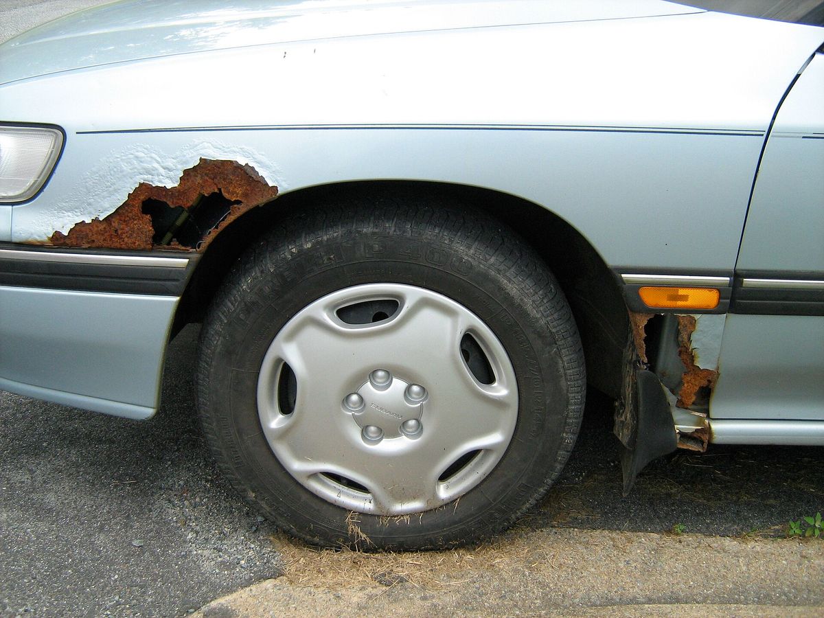 Rust and bubbling paint spreading across a steel car fender